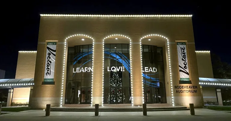 Commercial Christmas lighting outlining a large brick building at night.