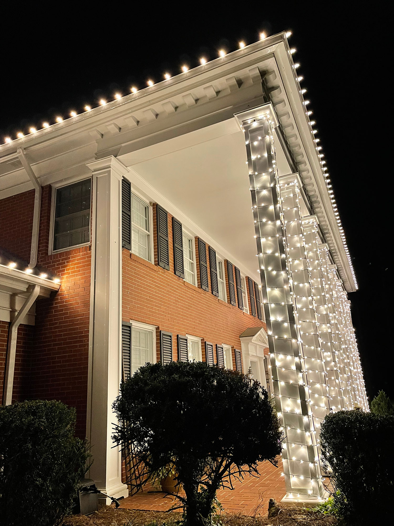 Warm-white C9 roofline bulbs and light-wrapped porch columns.